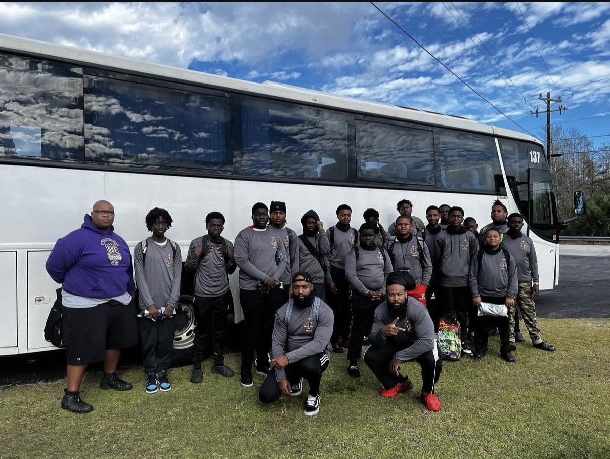 Athletic group standing in front of a JGT coach